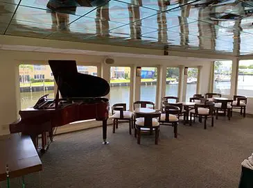 A piano is in the middle of a room with chairs.