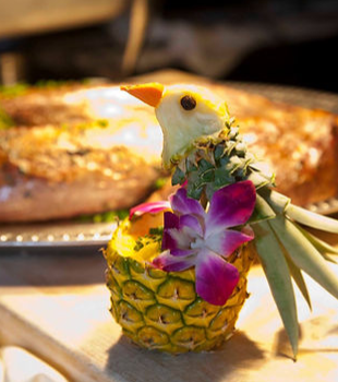 A pineapple with flowers and a bird on top of it.