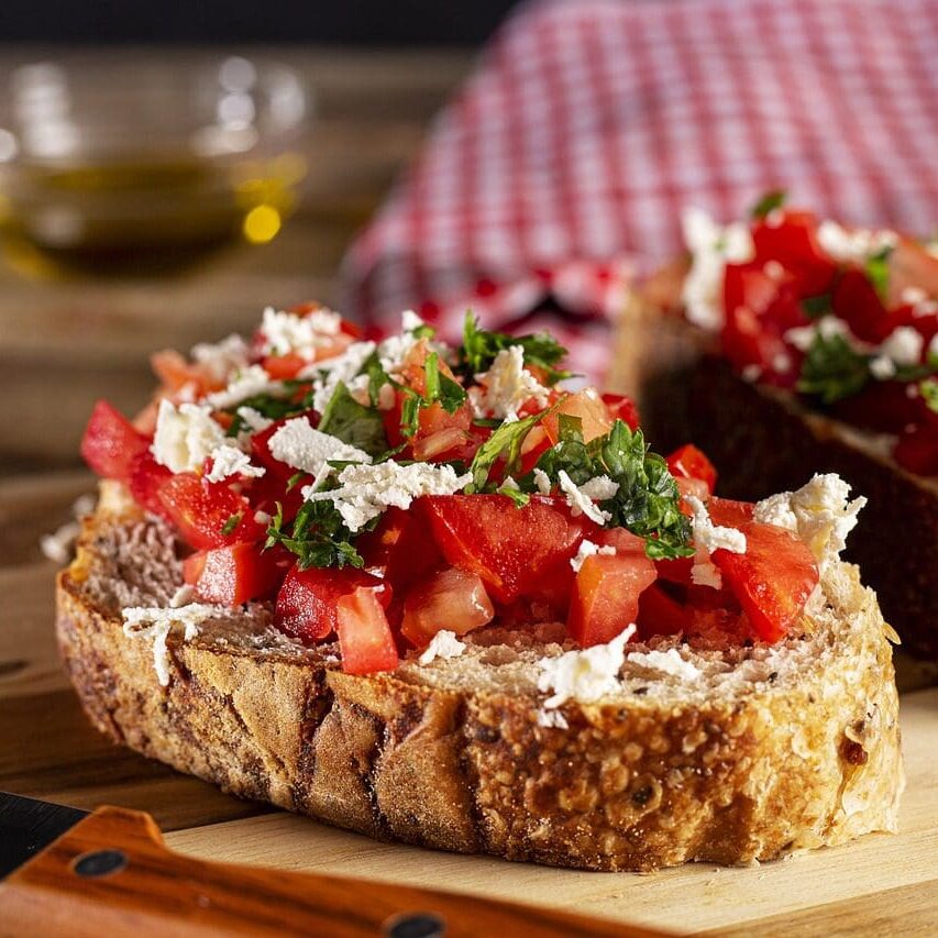 A piece of bread with tomatoes and feta cheese on it.