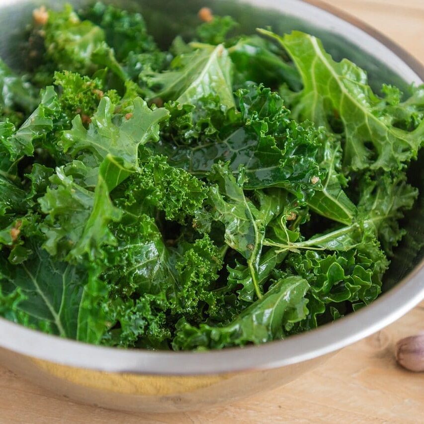 A bowl of green leafy vegetables on top of a table.