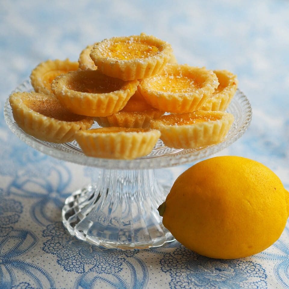 A glass plate with lemon and some little tarts