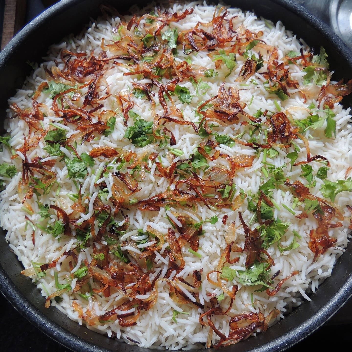 A pan of rice with onions and broccoli.